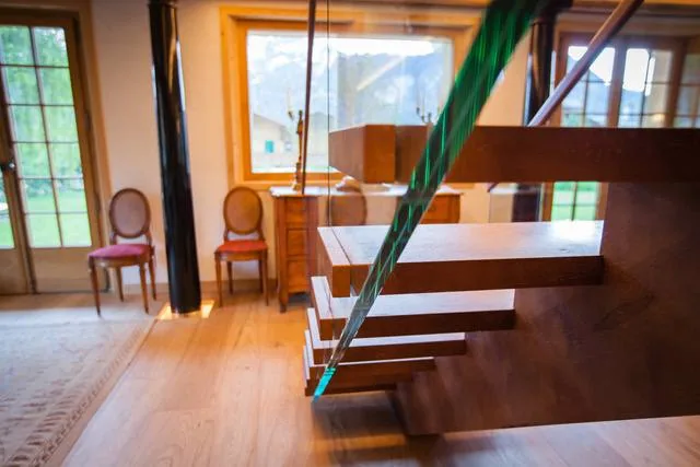 Escalier suspendu en bois avec garde-corps en verre et câbles métalliques