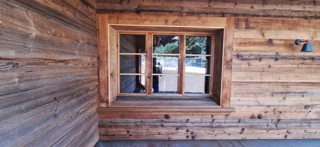 Fenêtre en bois intégrée à la façade rénovée d’un chalet ancien