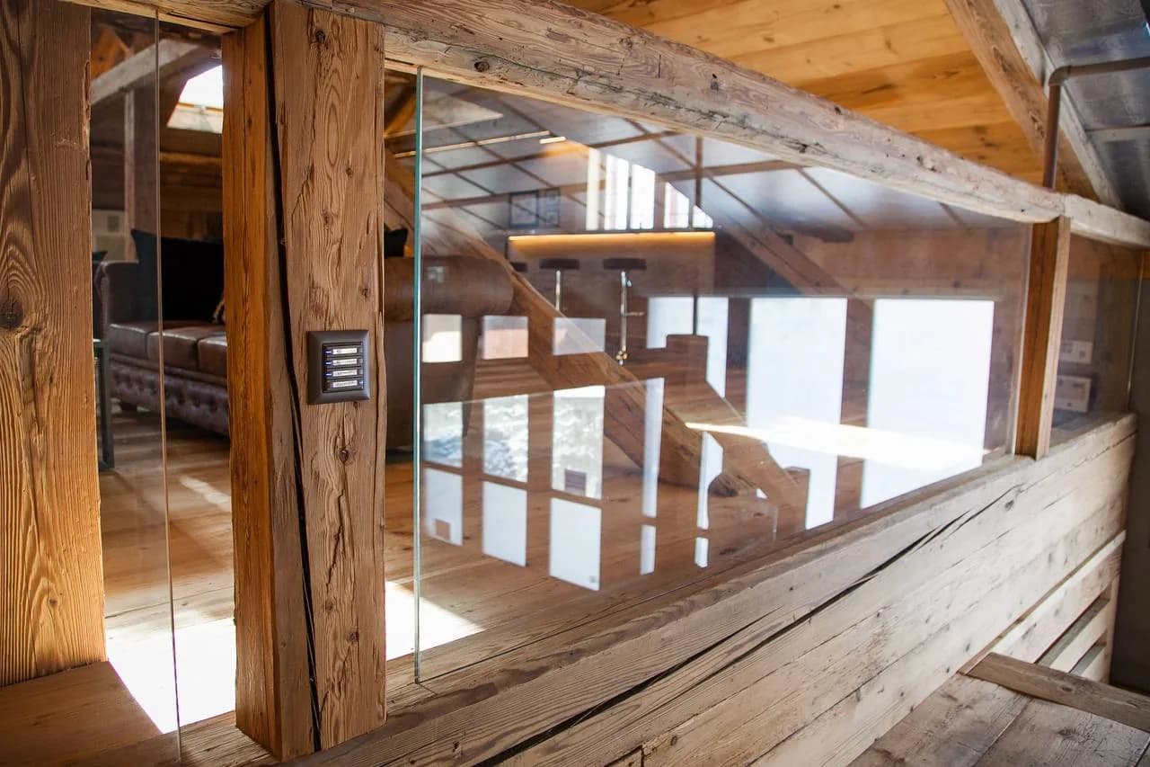 Garde-corps en verre intégré à une structure intérieure en bois ancien