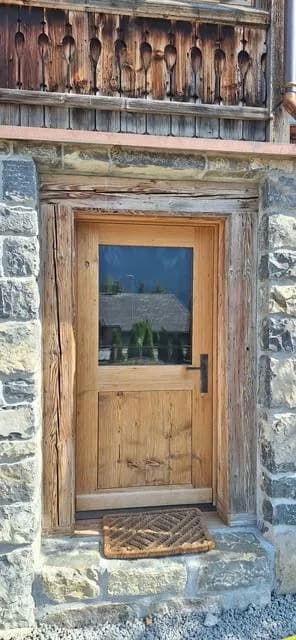 Porte d’entrée en bois posée dans un encadrement en pierre